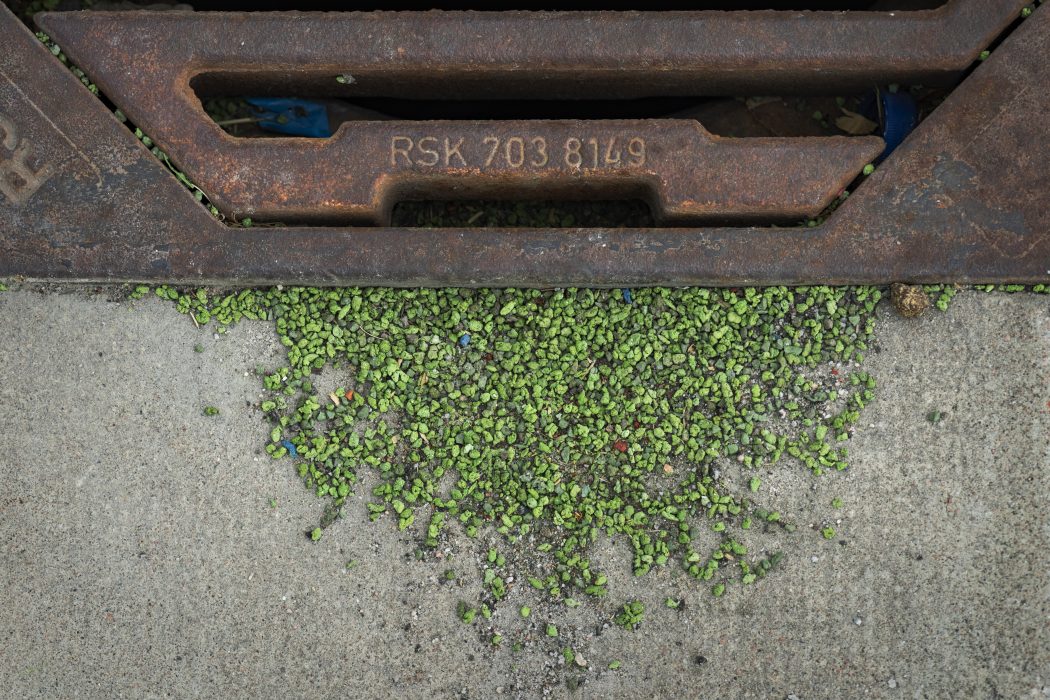 Dagvattenbrunn vid en konstgräsplan med gummigranulat av mikroplast.