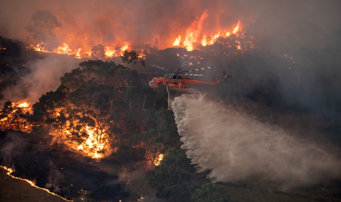 En helikopter vattenbombar bränderna i East Gippsland-området i delstaten Victoria.