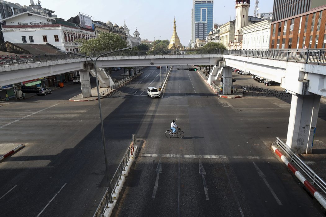 En cyklist på en glest trafikerad gata i staden Rangoon i Myanmar.
