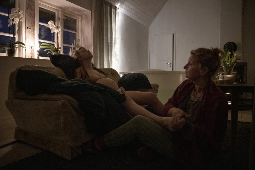 Madelen får fotmassage av barnmorskan Sandra under värkarbetet hemma i vardagsrummet.