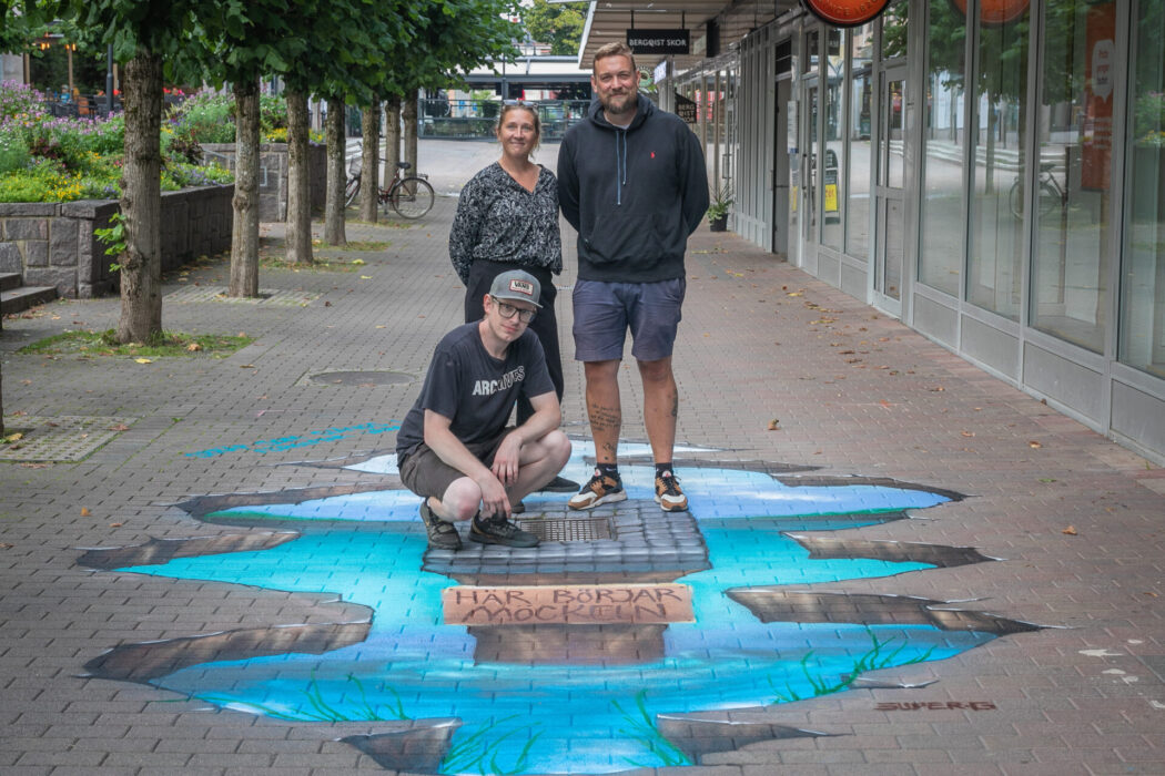 Konstnären Robert Forsberg, sittande, har gjort den här målningen i centrala Karlskoga för att nedskräpningen av sjön Möckeln ska minska.