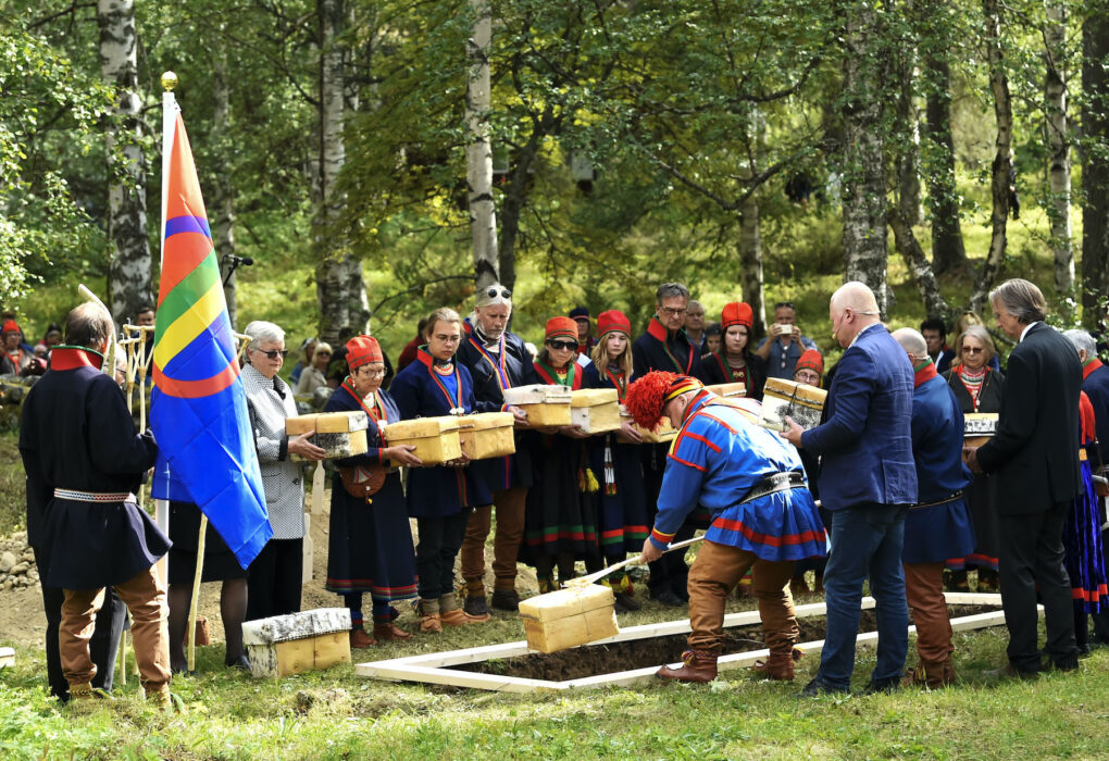  En av 25 näveraskar som innehåller kvarlevor sänks ner under återbegravningen på försoningsceremonin vid Gammplatsen i Lycksele, 9 augusti 2022.
