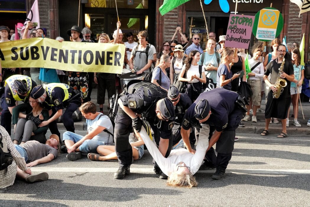 Polisen bär bort aktivister från Extinction rebellions demonstration på Kungsgatan 19 augusti 2022.