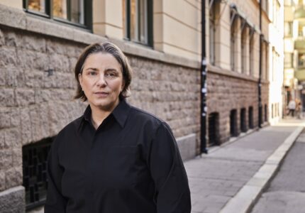 Anna Troberg framför en stenvägg på en gata.