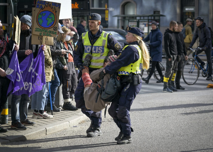 Två poliser bär bort en klimataktivist från en demonstration.